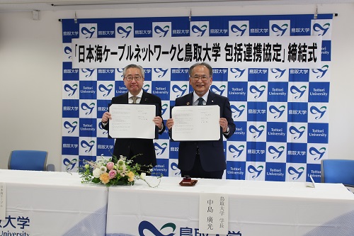 協定締結書を持つ中島学長と吉岡代表取締役社長